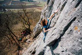 Frau klettert am Fels