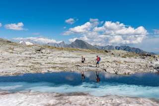 Zwei Menschen wandern im Gebirge an Gletscher entlang