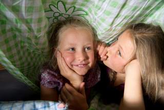 Zwei Mädchen tuscheln unter der Bettdecke
