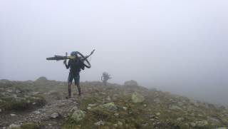 Menschen tragen Mountainbikes auf Bergweg im Nebel