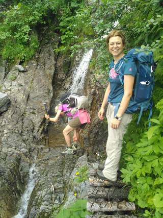 Zwei Frauen auf schmalem Steig mit kleinem Wasserfall