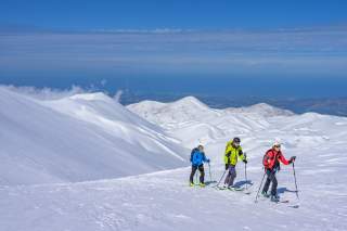 Drei Menschen auf Skitour mit Blick aufs Meer