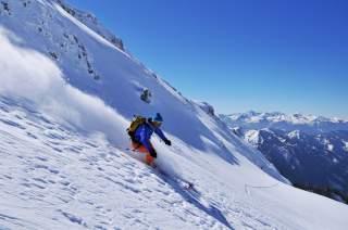 Skifahrer bei Abfahrt im Powder bei Sonnenschein