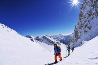 Truppe an Skitourengehenden beim Aufstieg in der Sonne