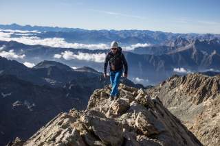 Wanderer auf Grat mit Gipfelkulisse