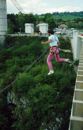Ralf Dujmovits springt gesichert von einer Brücke.