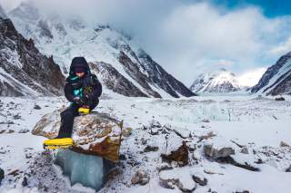 Tamar Lunger sitzt am Fuß des K2 auf einem Fellsblock