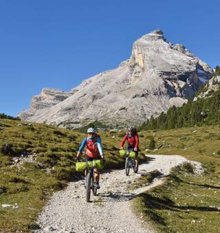 Zwei Mountainbiker auf einem Bergweg mit Gipfel im Hintergrund