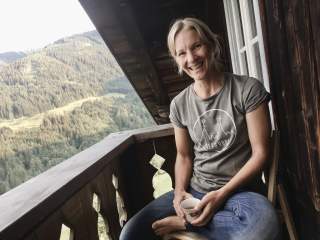 Frau sitzt auf Balkon von Holzhütte