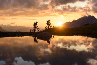 Zwei Menschen auf Mountainbikes im Sonnenuntergang