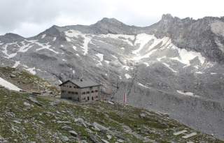 Berghütte vor Schlucht, gegenüber ragt ein felsiges Kar auf