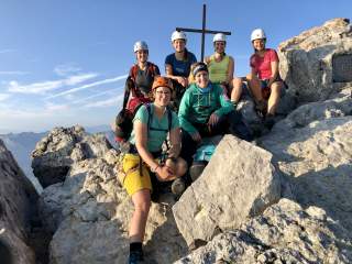 Eine Gruppe Frauen mit Kletterausrüstung am Gipfelkreuz