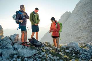 Drei Menschen am Berg ziehen nach der Pause wieder Jacken an