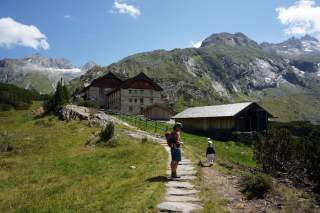 Frau mit Kind wandert auf Berghütte zu