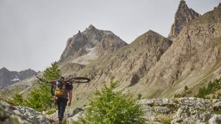 Mensch trägt Mountainbike durch Berglandschaft