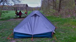 Ein blaues Zelt auf grüner Wiese, man sieht, es ist noch kalt und hat geregnet.