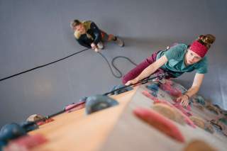 Frau klettert in Halle, Mann sichert toprope
