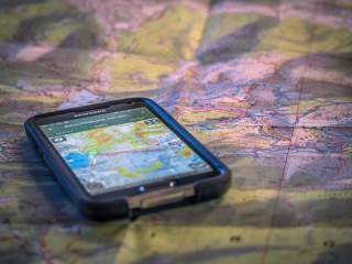 Smartphone mit Tourenplanungs-App auf analoger Landkarte