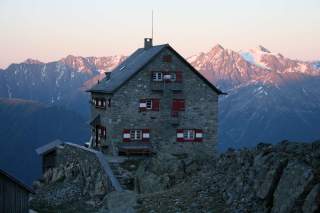 Hütte im Abendrot vor Gipfeln