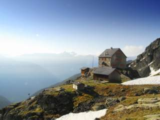 Zum Beginn der Hüttensaison: Eine große Alpenvereinshütte thront auf einer Wiese über dem Ötztal.
