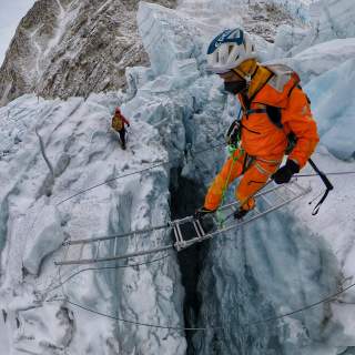 David Göttler auf einer Leiter über einer Gletscherspalte
