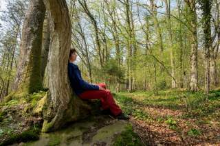 Frau lehnt an Baum im Wald