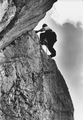 Schwarz-Weiß-Foto von Mann beim Klettern