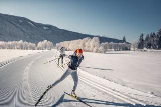 Eine Langläuferin skatet auf einer winterlichen Loipe.