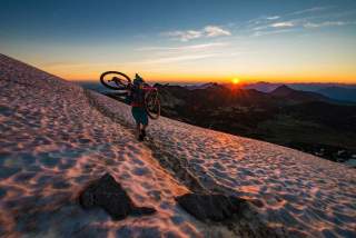 Mountainbikerin trägt Rad über Schneefeld