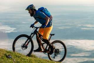 Mountainbiker fährt steile Bergwiese hoch