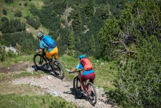 Zwei Menschen fahren mit Mountainbikes einen Bergtrail runter