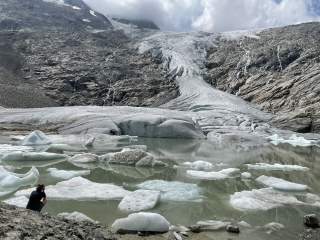 Frau sitzt vor Gletschersee und bestaunt Gletscher