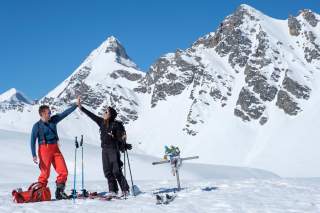 Zwei Menschen klatschen auf verschneitem Gipfel ab