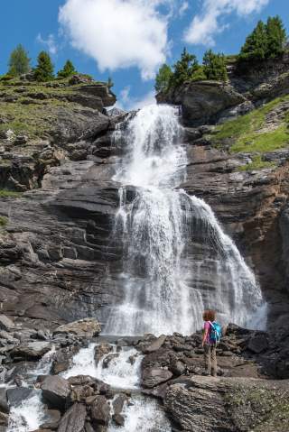 Frau steht vor imposantem Wasserfall