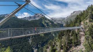 Frau wandert auf langer Hängebrücke in den Bergen