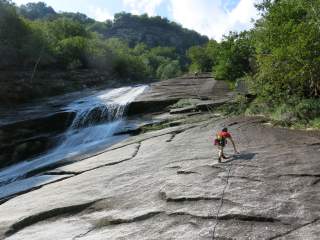 Zwei Kletternde an Fels neben Wasserfall