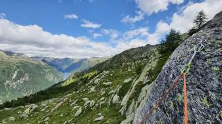 Fels mit Kletterseil und Ausblick auf Stausee