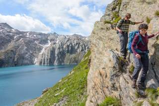 Zwei Menschen steigen in schmaler Felskante über See ab