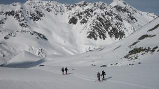 Skitourengeher*innen vor schneebedeckten Bergen.