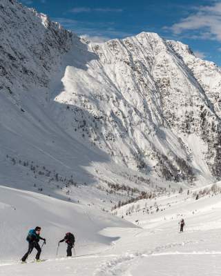 Skitourengehende inmitten schneebedeckter Bergwände.