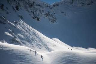 Zwei Menschen auf Skitour unter schneebedecktem Hang