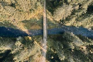 Luftaufnahme: Zwei Menschen auf Rädern queren Fluss über Brücke