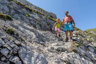 Mann hilft Kind beim Wandern in felsigem Gelände