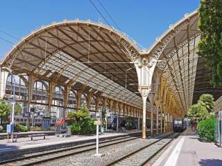 Zwei große, gewölbte Stahlgerüstdächer am Hauptbahnhof Nizza. Strahlend blauer Himmel.