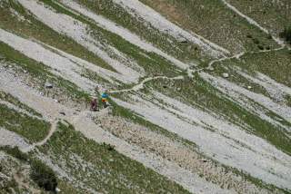 Zwei Menschen mit Mountainbikes in Hang auf schmalem Bergweg
