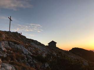 Gipfelkreuz und kleine Hütte in der Abenddämmerung
