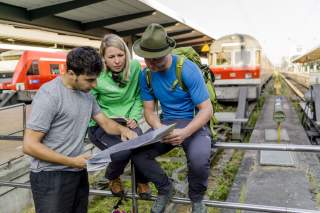 Drei Menschen studieren Karte am Bahnhof