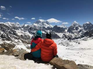Zwei Menschen machen Pause am Berg mit Blick auf Mount Everest