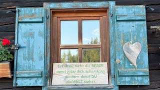 Schild mit Spruch an Hüttenfenster
