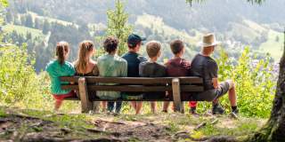 Jugendliche sitzen auf Bank am Berg
